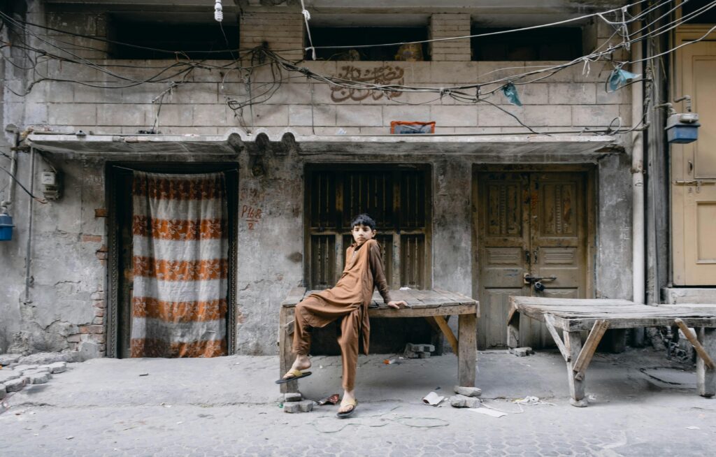 pexels-photo-3632710-3632710 Boy in traditional attire posing outside a rustic house in Faridabad, India.